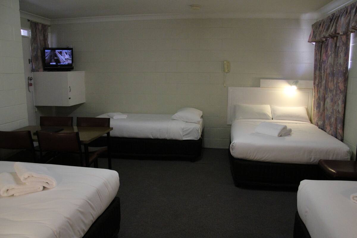 A hotel room with two single beds, a desk, a chair, a television, and a telephone.