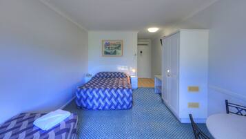 A small, neatly arranged room with a bed, a bedside table, a chair, and a wardrobe.