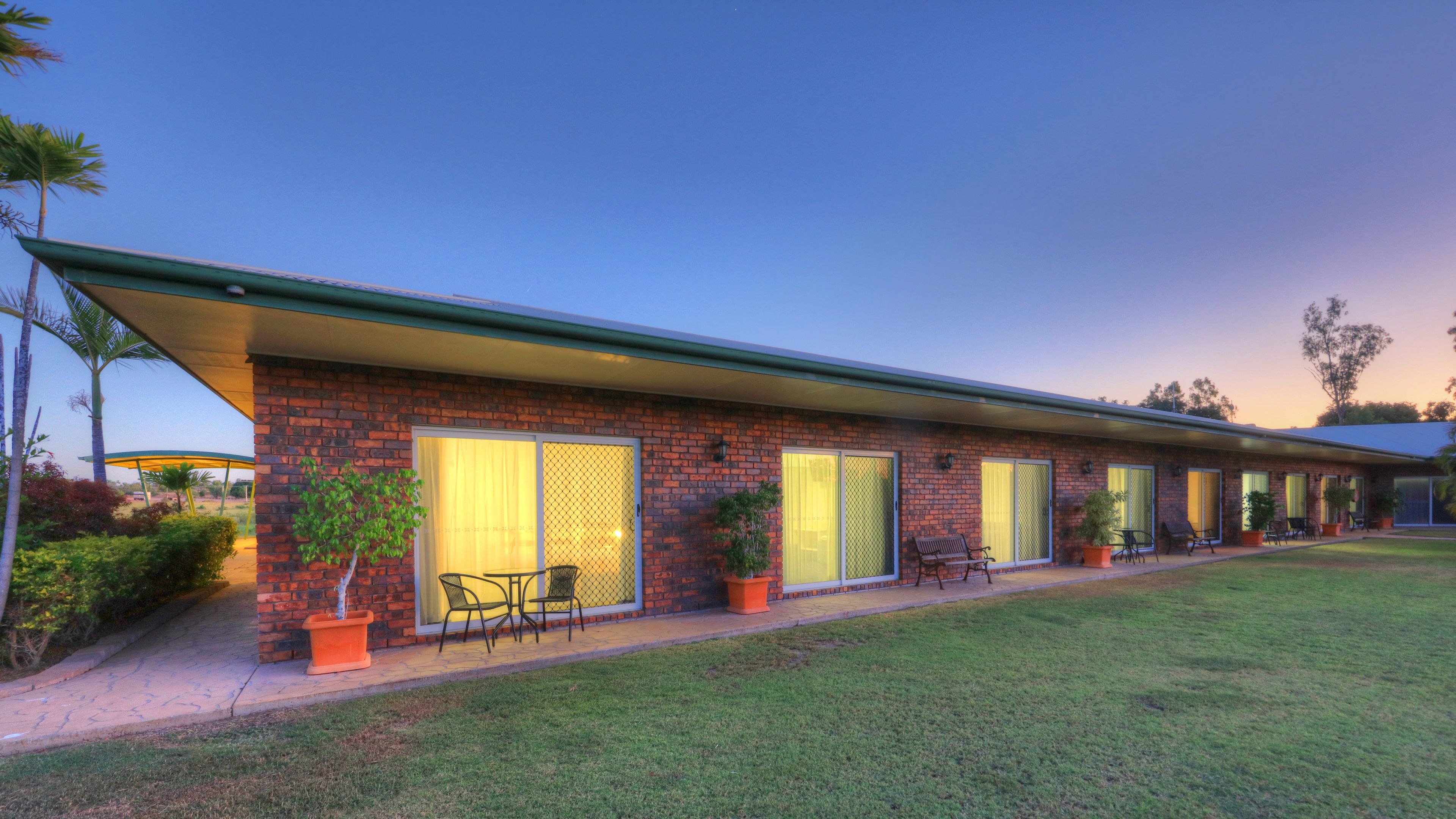 A modern building with a brick facade, large windows, and outdoor seating.