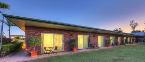 A modern building with a brick facade, large windows, and outdoor seating.