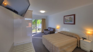 Ein Hotelzimmer mit Bett, Sofa, Fernseher, einem Gemälde und einem Fenster mit Vorhängen.