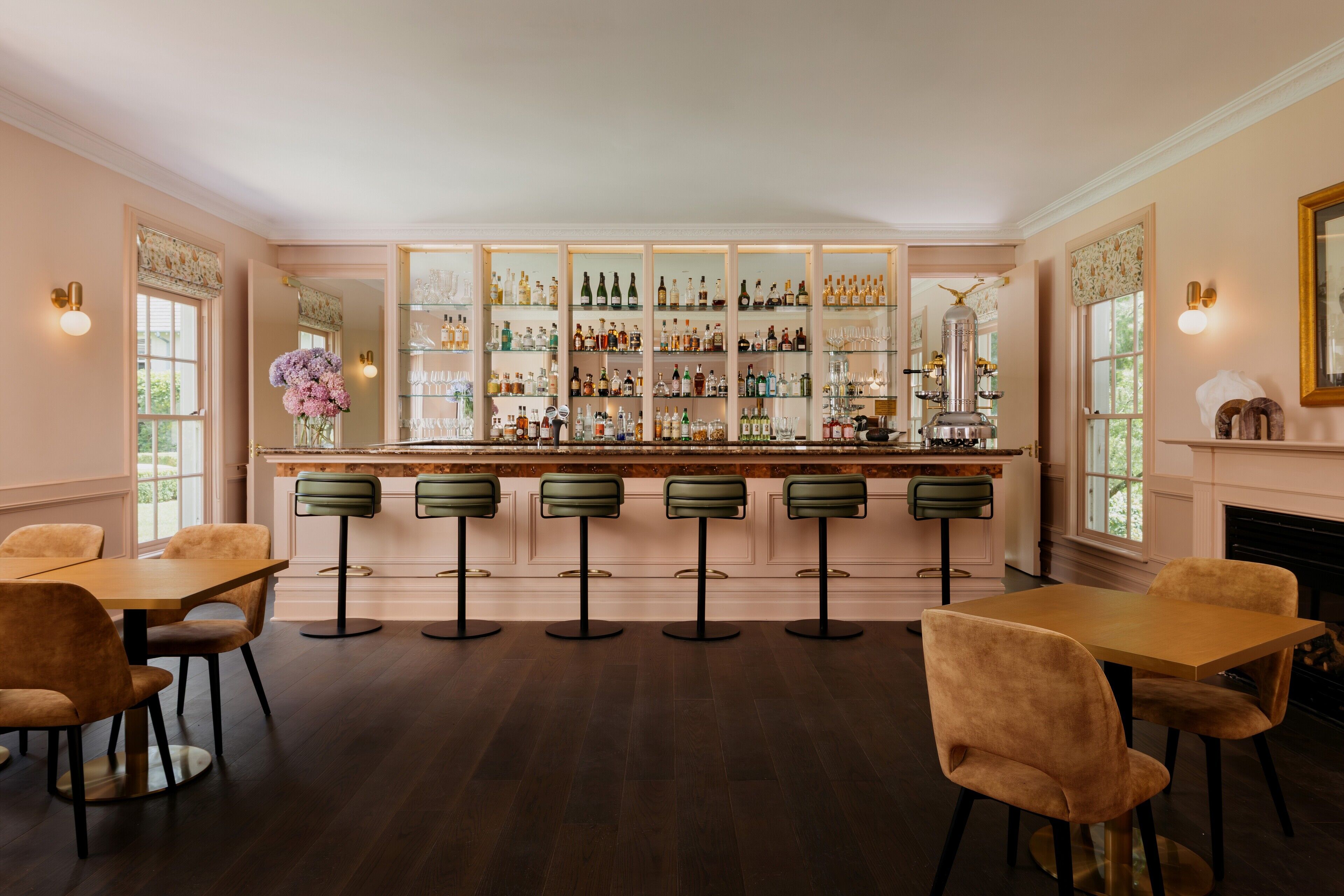 A bar area with a long counter, multiple stools, and a variety of bottles and glasses.