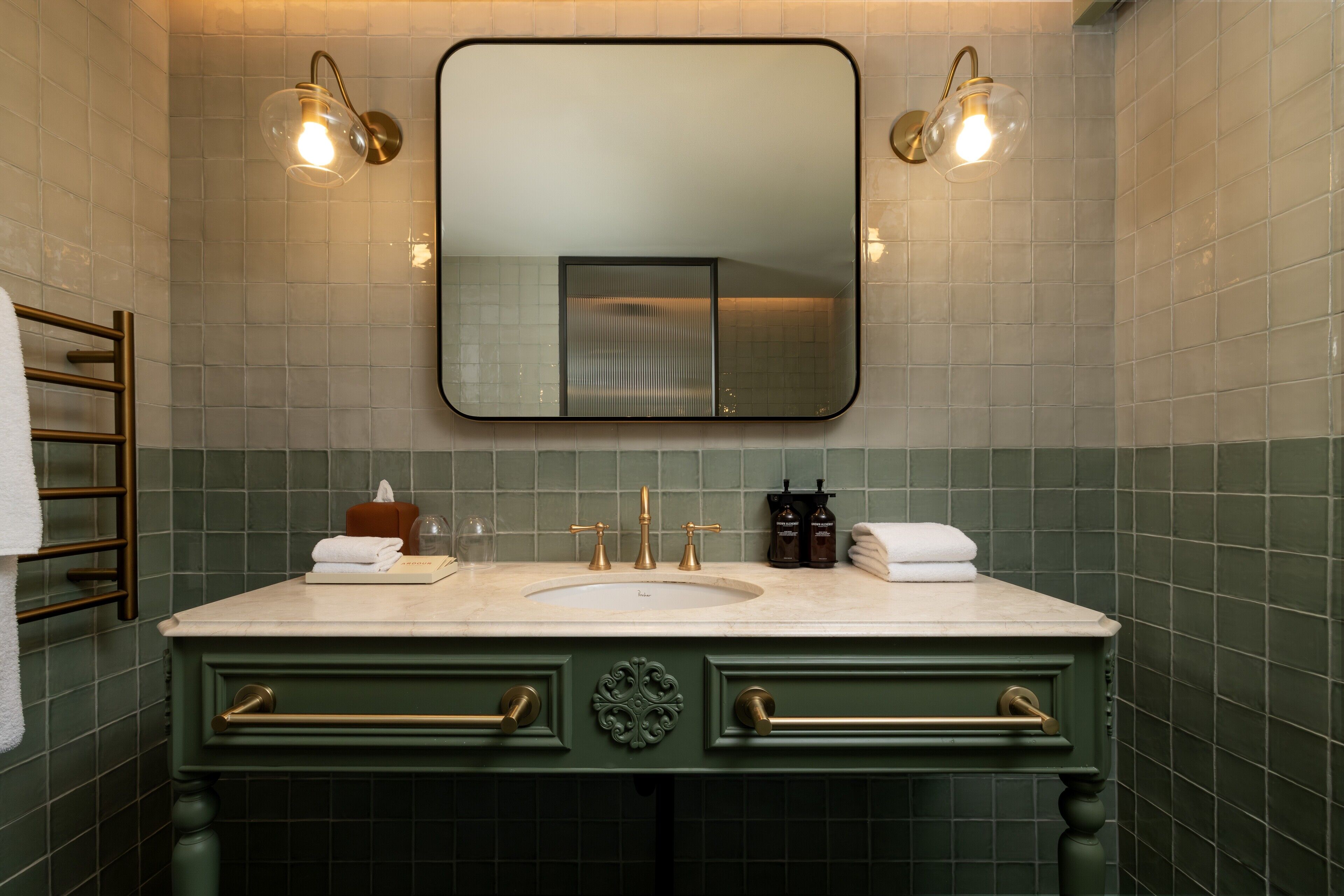 Un bagno con uno specchio grande, due luci a parete, un lavandino e un porta asciugamani.