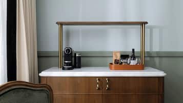 A wooden cabinet with a marble countertop, a coffee maker, and a tray with bottles and glasses.