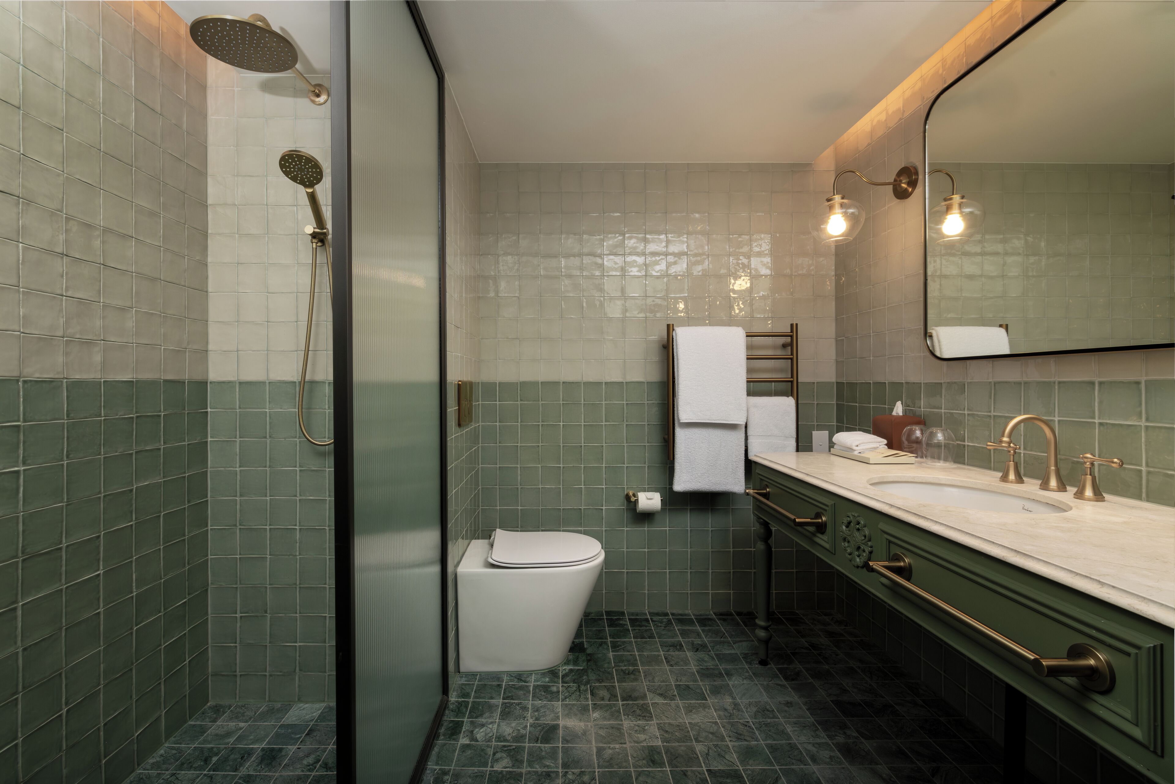 A bathroom with a shower, toilet, sink, and mirror.