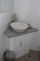 Un bagno con un lavandino bianco su un piano in granito, uno specchio sopra e un water a sinistra.