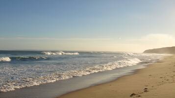 Enjoy a serene beach experience with gentle waves lapping onto the shore.