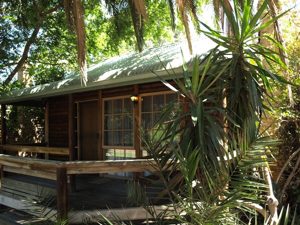 Una cabaña de madera con techo inclinado, ventanas amplias y una terraza de madera.