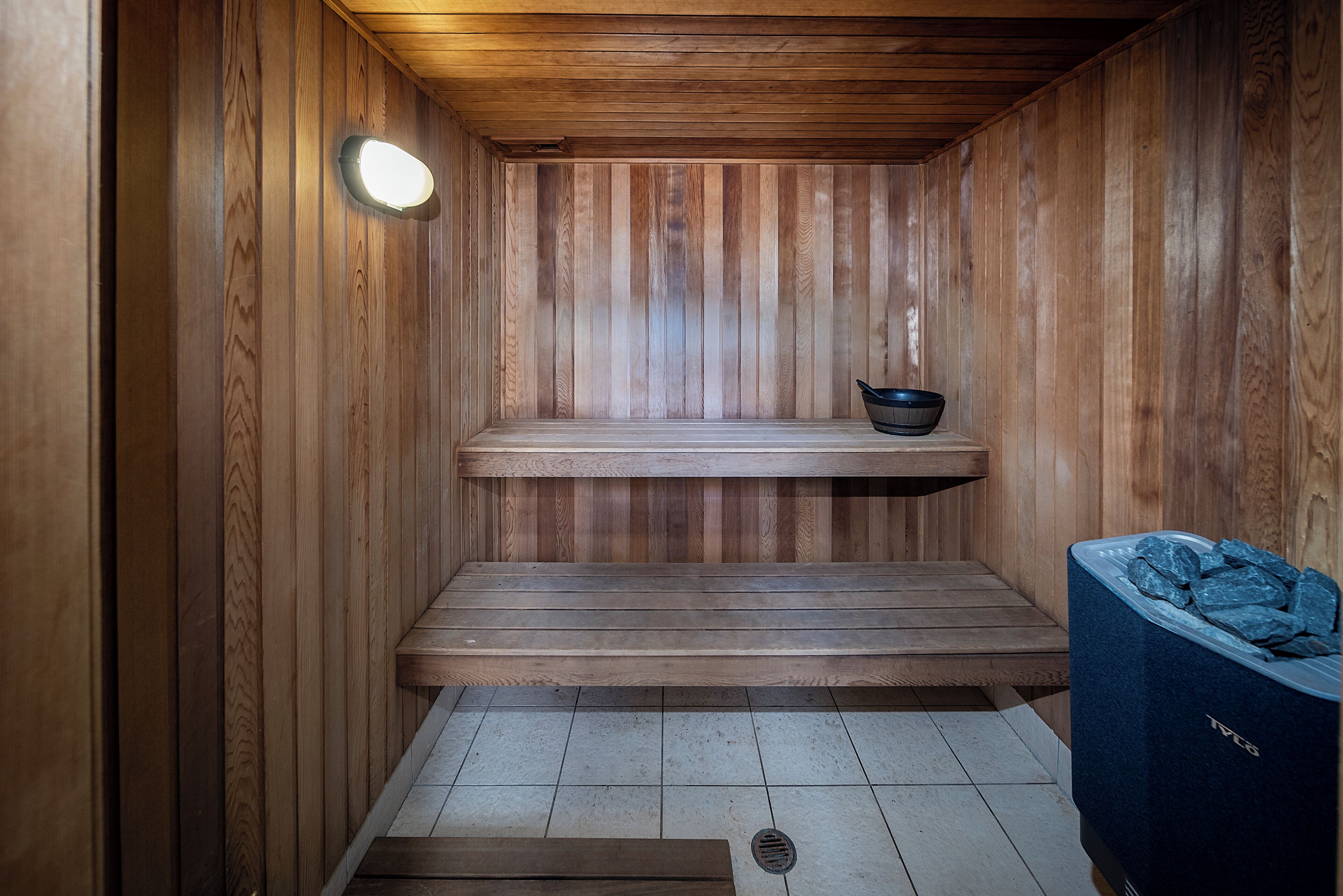 Una sauna in legno con una panca, uno scaffale e un cestino.