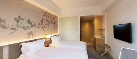 Habitación de hotel con dos camas, un mural grande en la pared, un televisor y un escritorio.