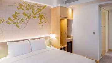 A hotel room with a large bed, a nightstand, a wall-mounted lamp, and a wardrobe.