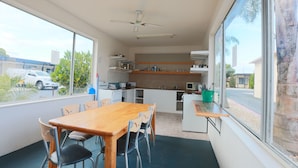 Una cocina funcional con comedor, ventanas amplias y ventilador de techo.