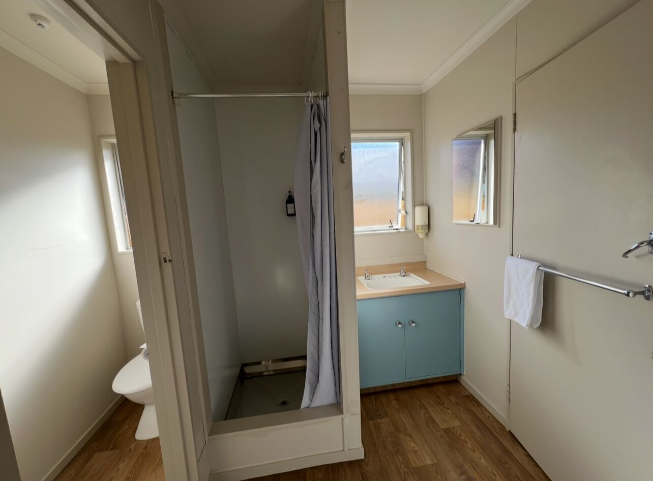 A bathroom with a shower, toilet, sink, and a towel rack.