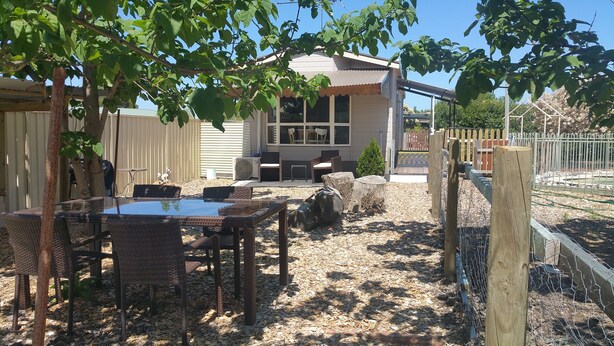 An outdoor patio area with wicker furniture, a glass table, and a seating arrangement. - Must Love Dogs B&b (Rutherglen)