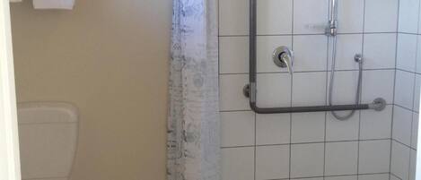 Un baño con ducha, inodoro y barra para toallas.