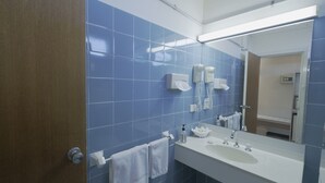Un baño con azulejos azules, un lavamanos blanco, un espejo y dos toallas colgadas en la pared.