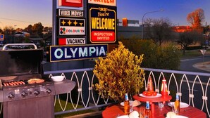 Un motel con letrero de neón, asientos al aire libre y una parrilla.