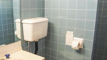 Un baño con inodoro, lavamanos y paredes de azulejos azules.
