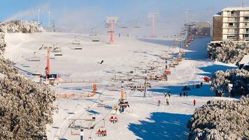 A ski resort with multiple ski lifts, a building with multiple floors, and snow-covered trees.