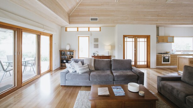 A spacious living room with a grey sofa, wooden flooring, and large windows. - Yallingup Villas (Yallingup)