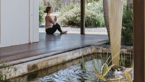A person sitting on a wooden deck with a pond and greenery in the background. - Yallingup Villas (Yallingup)