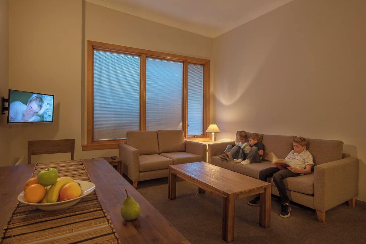 Een woonkamer met een bank, salontafel en een televisie aan de muur.