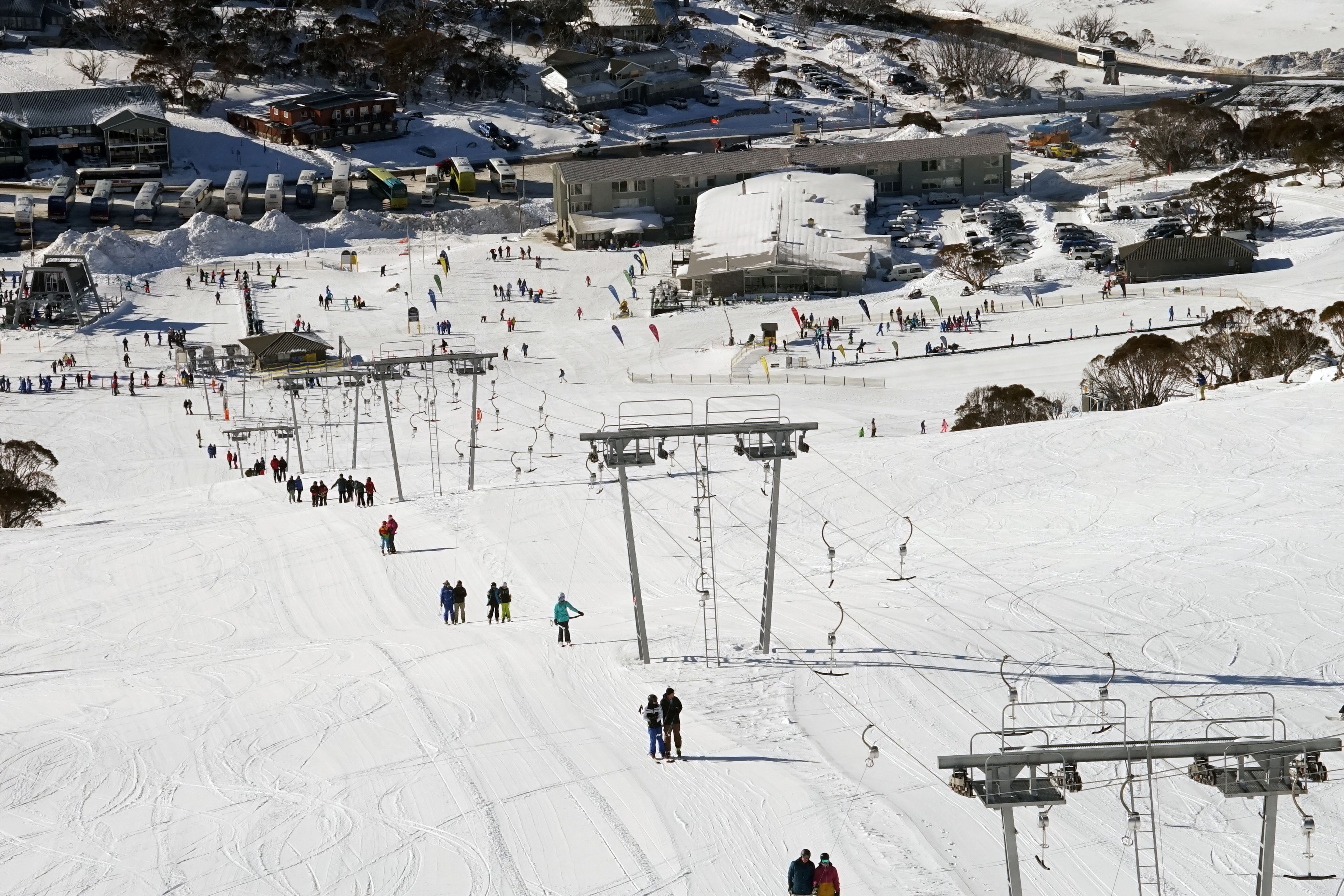 A ski resort with multiple ski lifts, a large open area for skiing, and buildings in the background.
