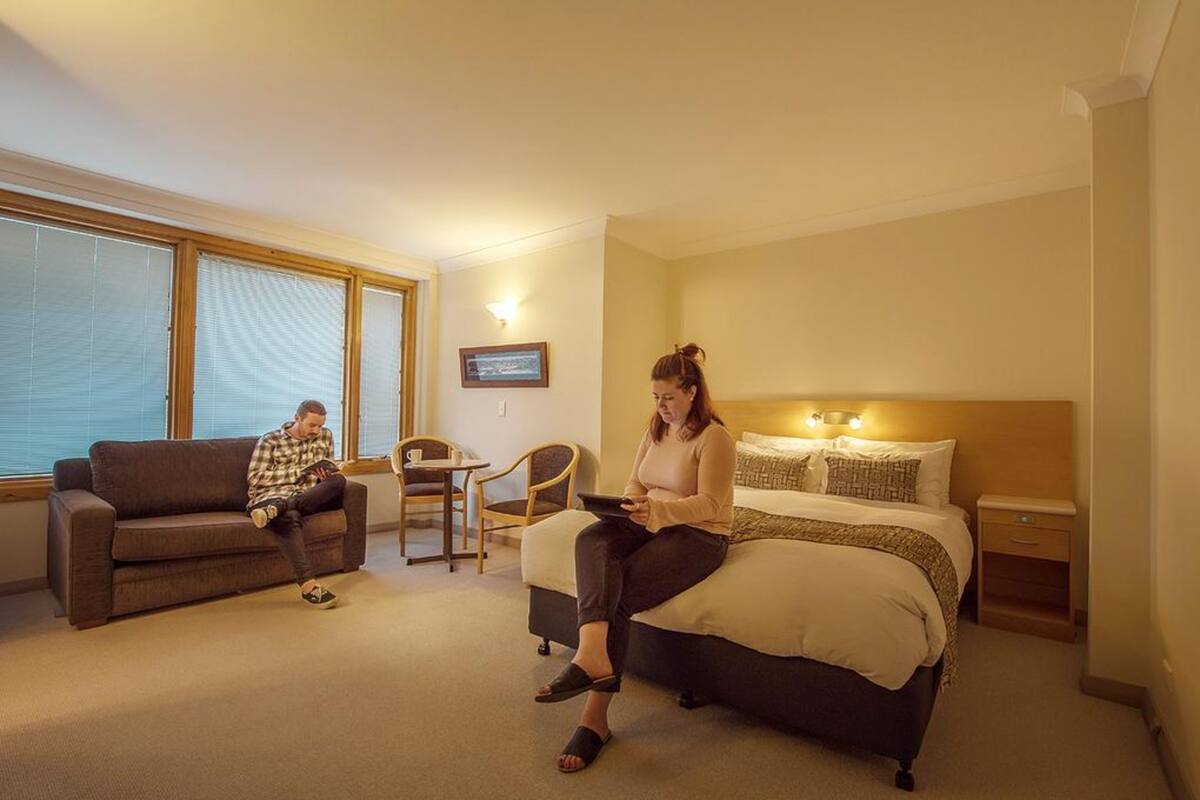 Een hotelkamer met een bed, een bank, een kleine tafel en een stoel.