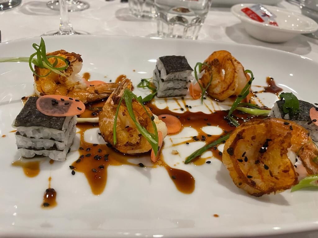 Une assiette blanche contenant différentes sortes de sushis et des accompagnements.