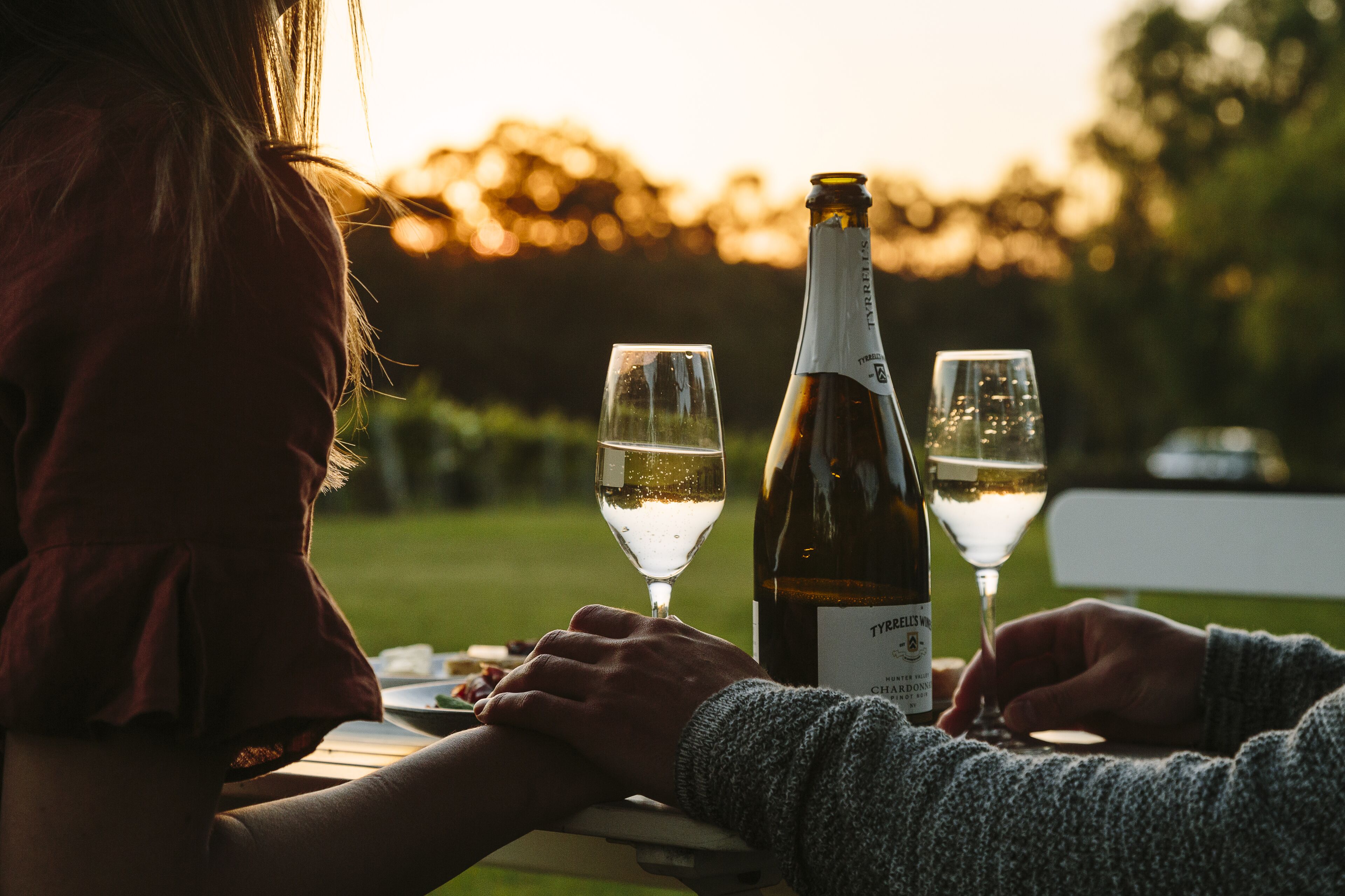 Two people sitting at a table with a bottle of wine and glasses.