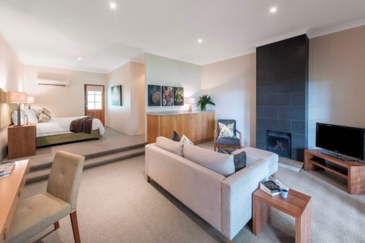 Una habitación de hotel moderna con sofá, televisión, chimenea y cama.