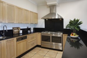 A modern kitchen with wooden cabinets, a stainless steel stove, and a black countertop. - Spicers Vineyards Estate (Pokolbin)