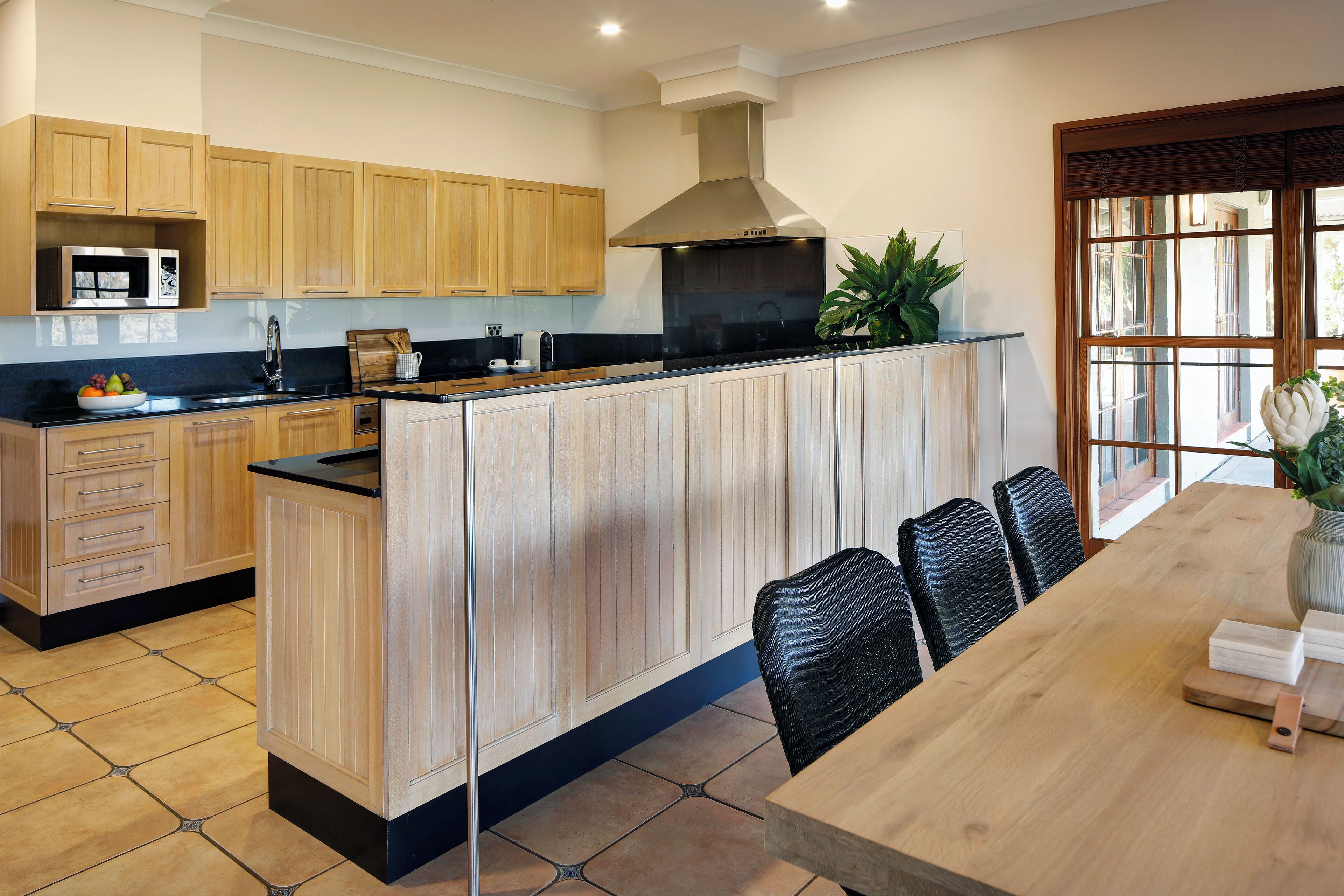 A modern kitchen with wooden cabinets, a black countertop, and a large island with seating.