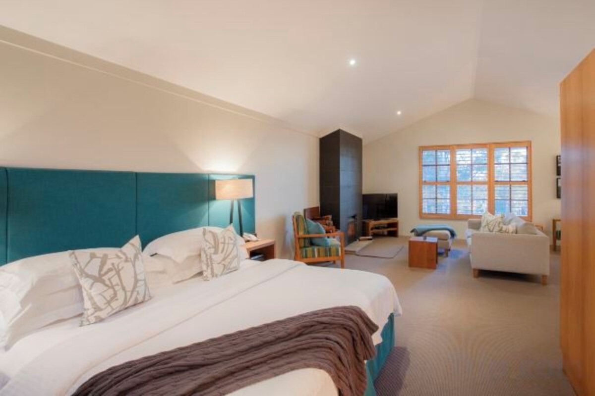 Una habitación de hotel con una cama grande, un televisor, un sofá y un mueble para televisión.