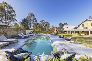 Zona junto a la piscina con sillones de descanso, una mesa de comedor y una vista despejada del paisaje circundante.