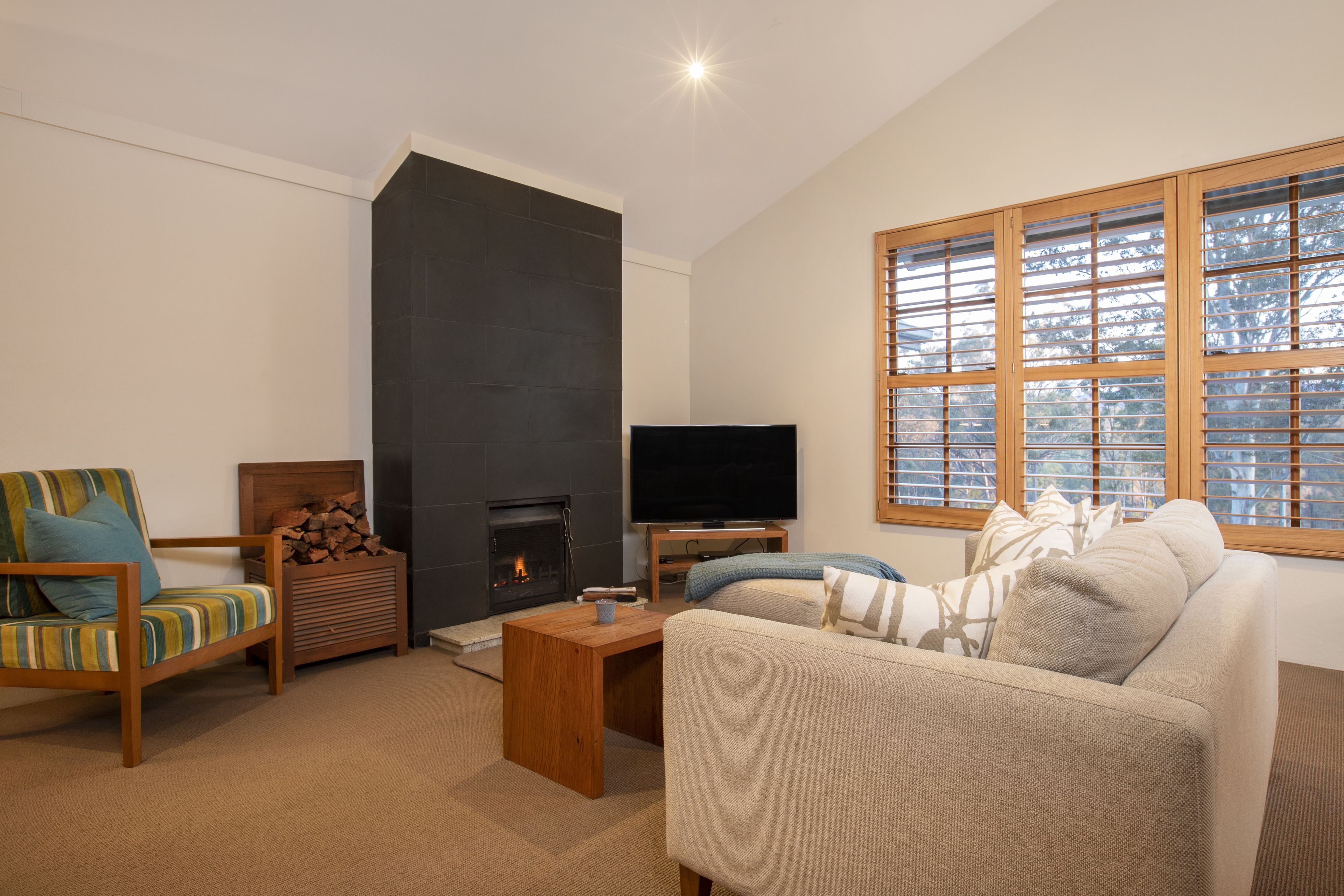 Una sala de estar con chimenea, televisor, sofá y sillón.