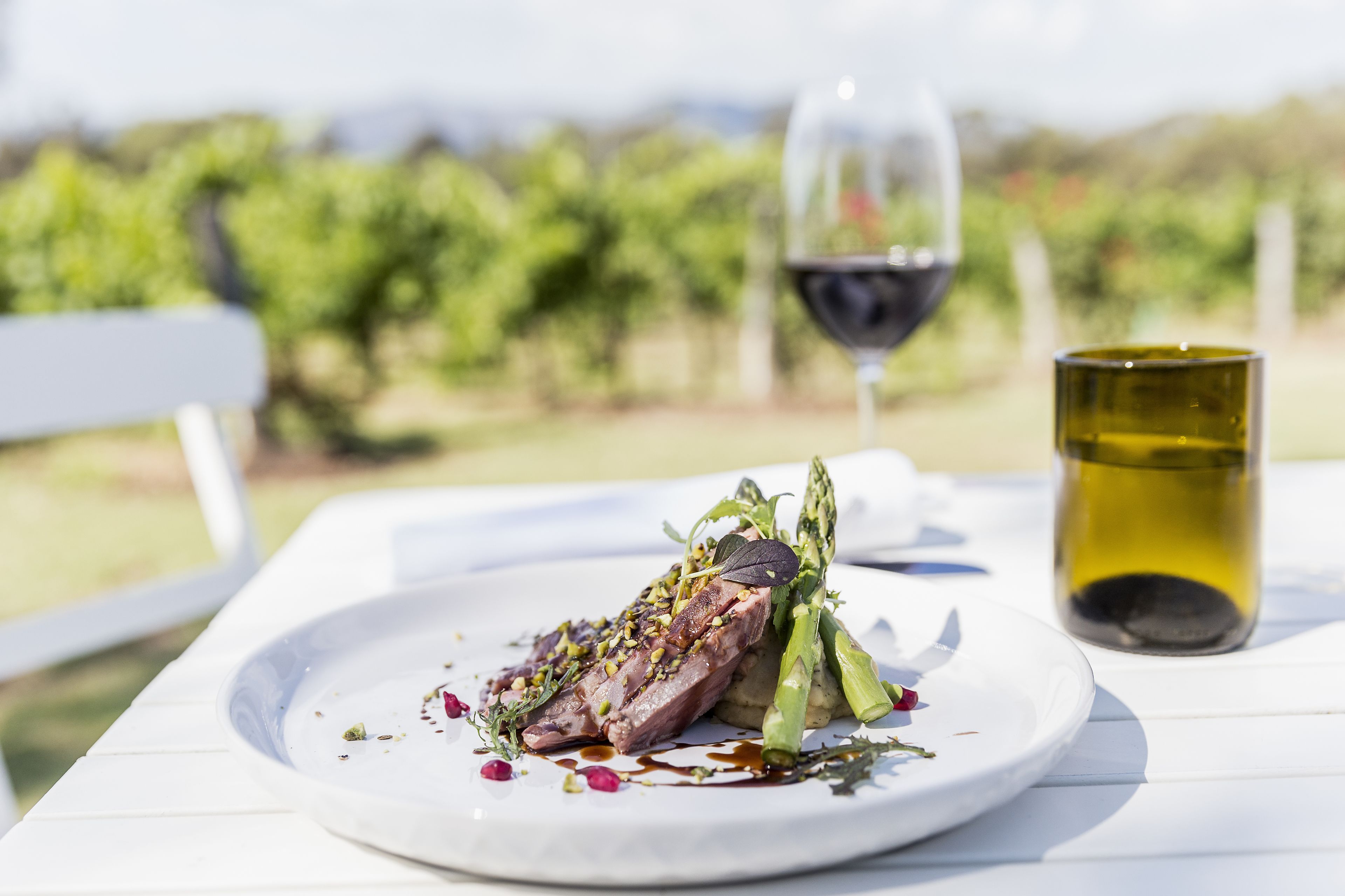 Un plato de comida con una copa de vino tinto y una copa de vino blanco sobre una mesa blanca.