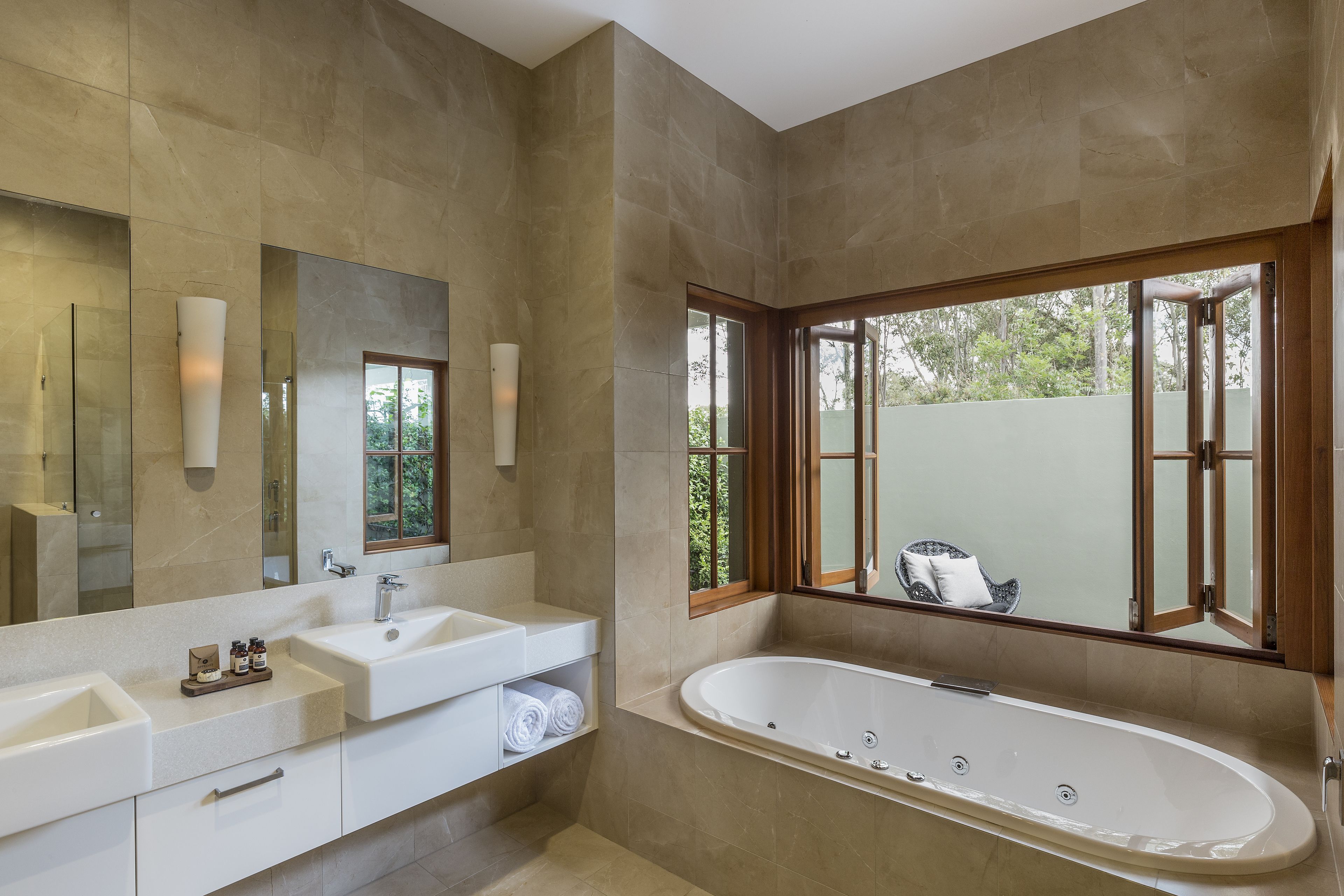Une salle de bain moderne avec une grande baignoire, deux lavabos et un grand miroir.