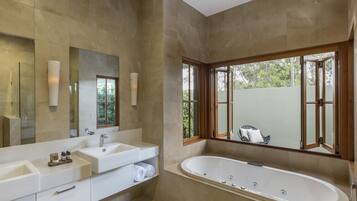 Une salle de bain moderne avec une grande baignoire, deux lavabos et un grand miroir.