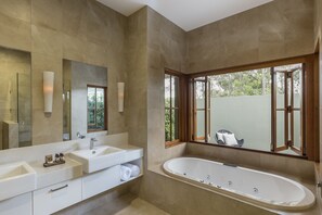 Un baño moderno con una bañera grande, dos lavamanos y un espejo amplio.