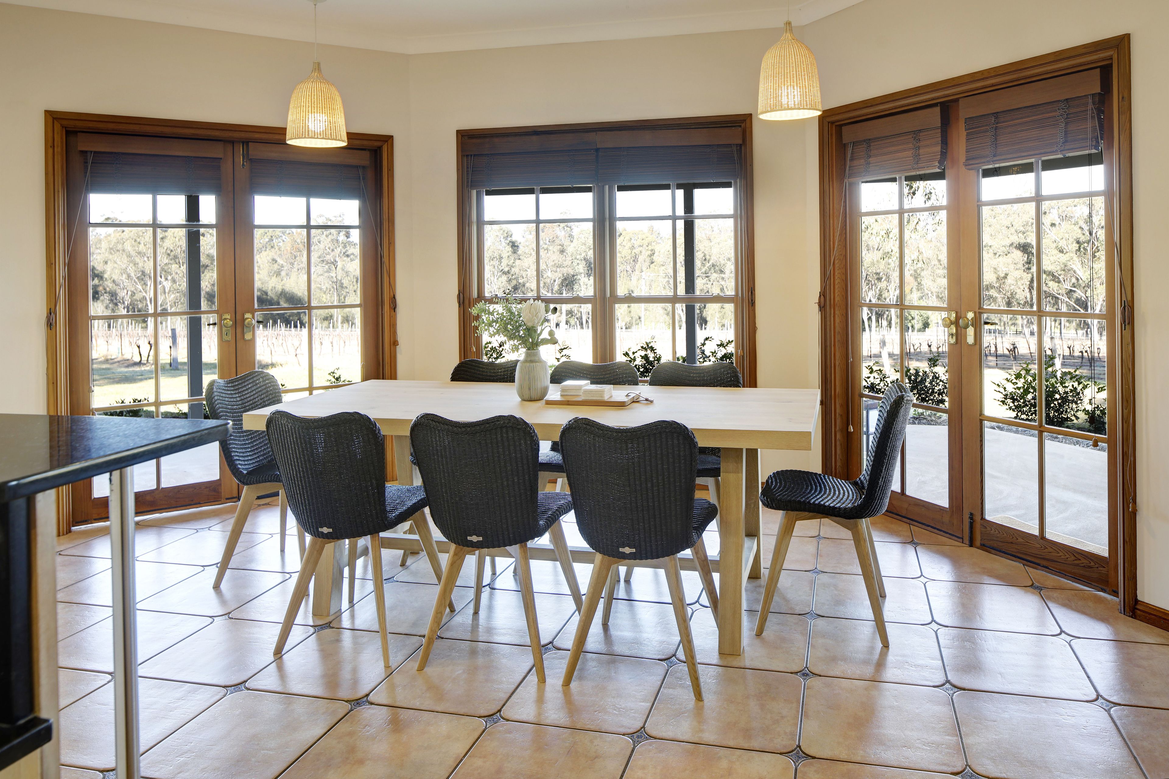 A dining area with a large table, six chairs, and two pendant lights.