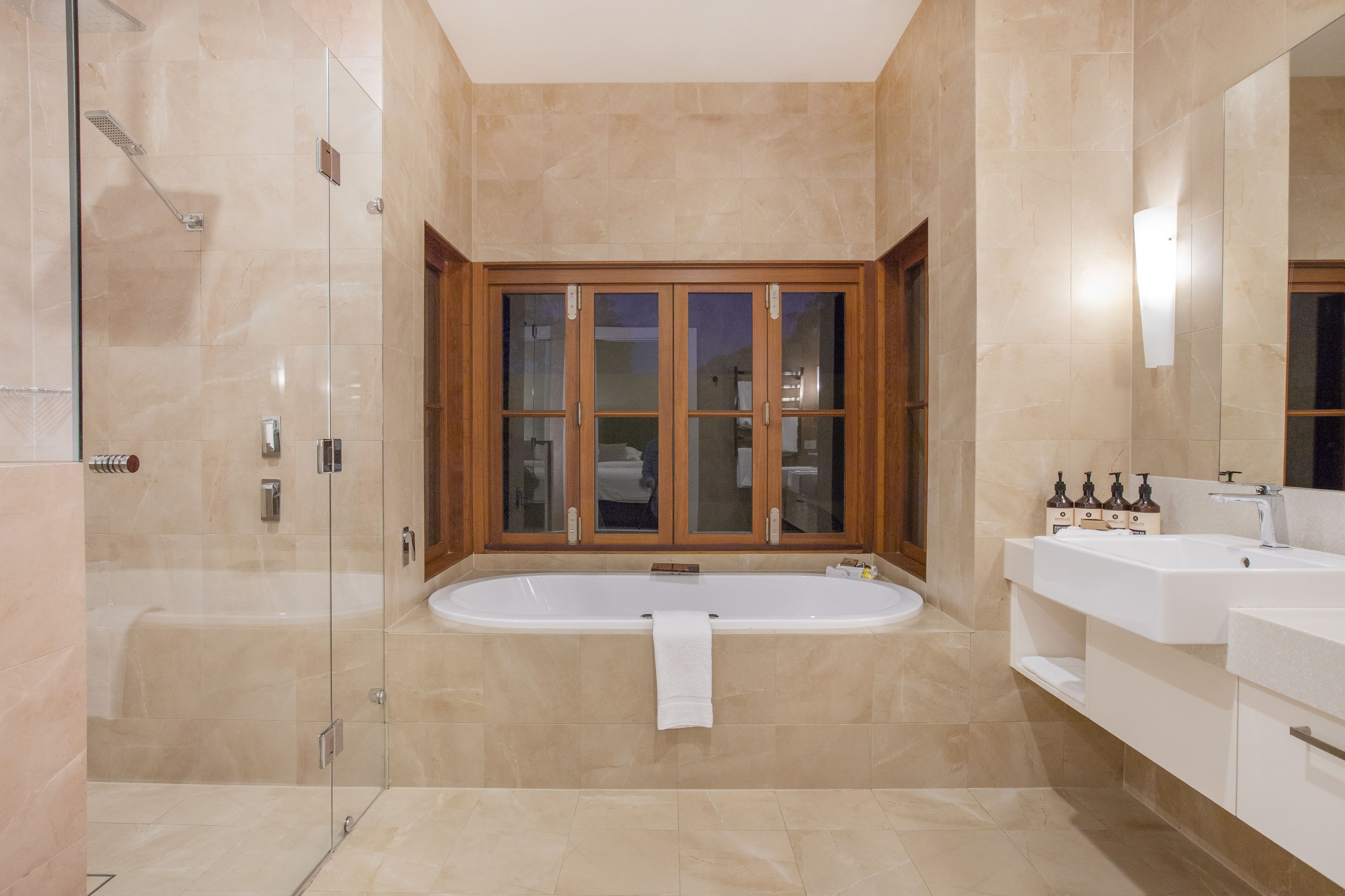 A modern bathroom with a glass-enclosed shower, a freestanding bathtub, and a vanity with a mirror.