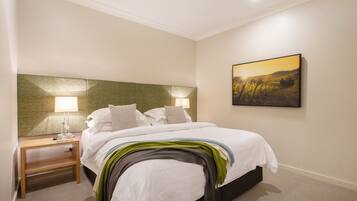 Una habitación de hotel con una cama, mesitas de noche, una lámpara y un cuadro en la pared.
