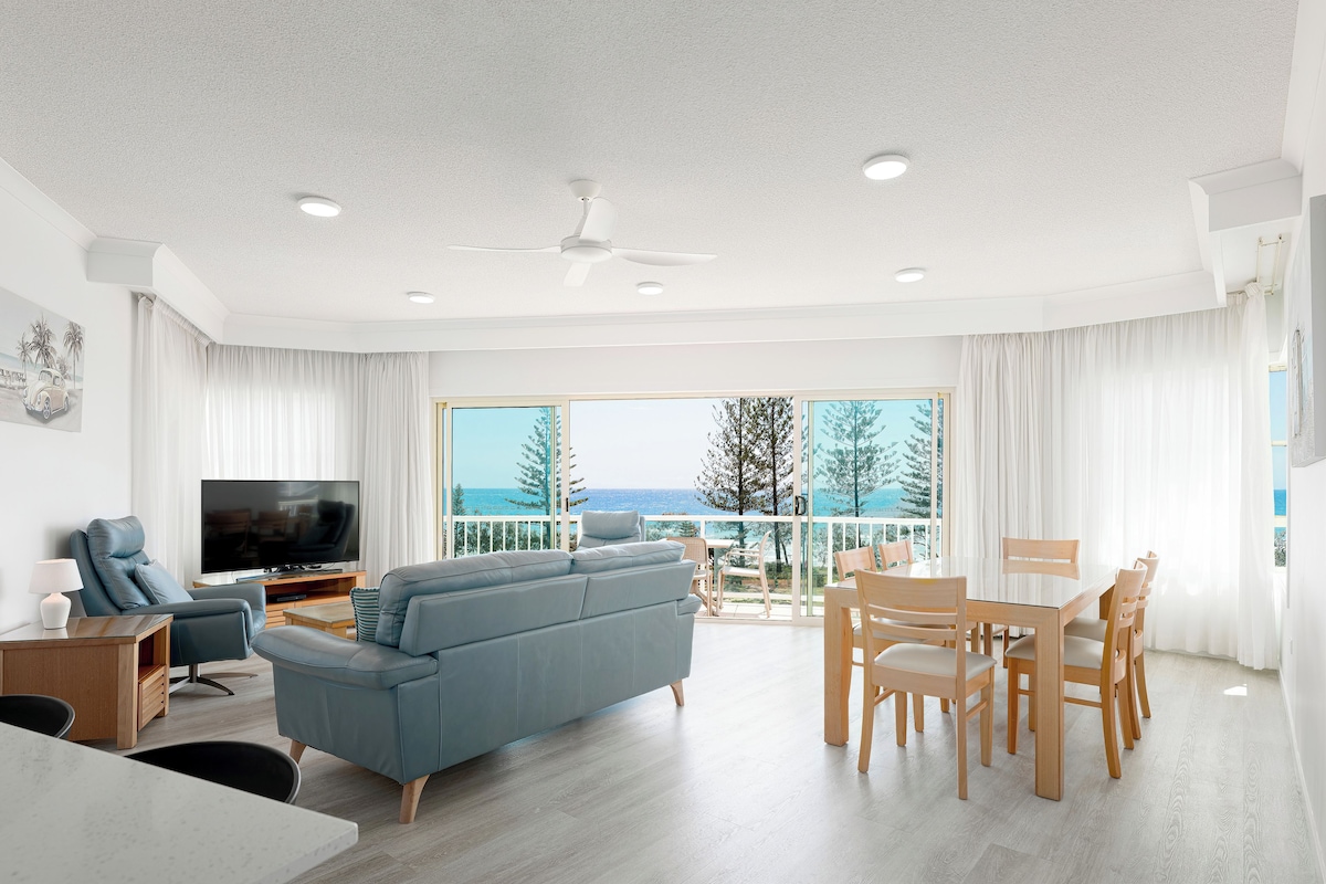 Una sala moderna con sofá, televisor y comedor, con vistas a un paisaje pintoresco.