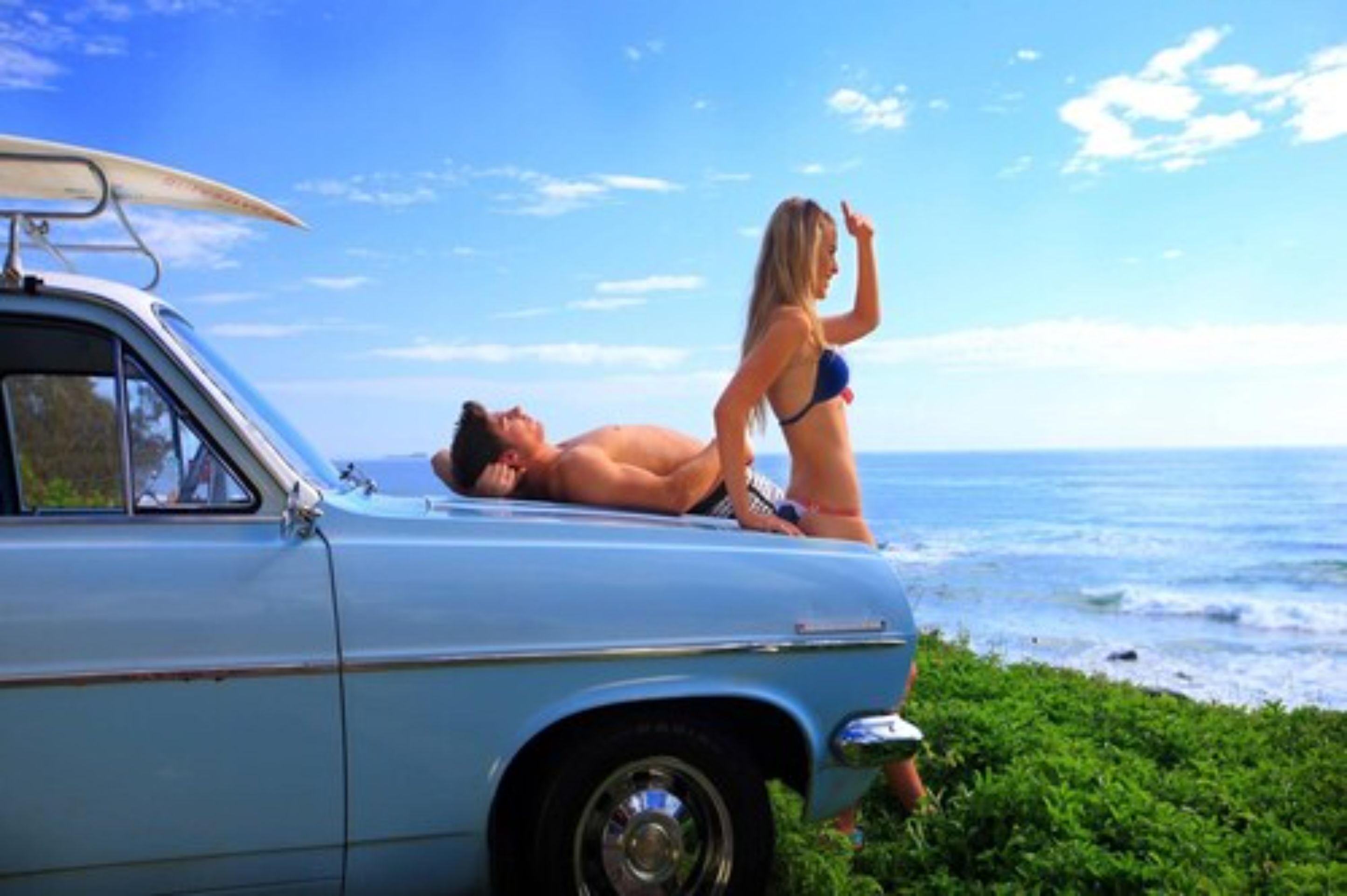 A vintage car parked by the seaside with a clear view of the ocean.