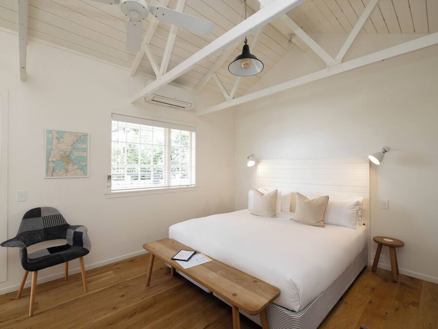 Une chambre à coucher avec un grand lit, un banc en bois, une chaise et une carte accrochée au mur.