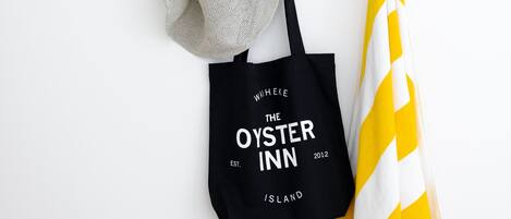 A wooden coat rack with a black tote bag and a yellow and white striped towel hanging on it.