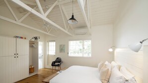 A bedroom with a large bed, a wardrobe, a desk, and a chair.