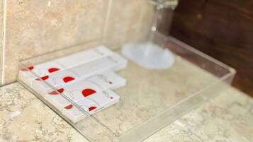 A bathroom with a marble countertop, a glass soap dish, and a shower area.