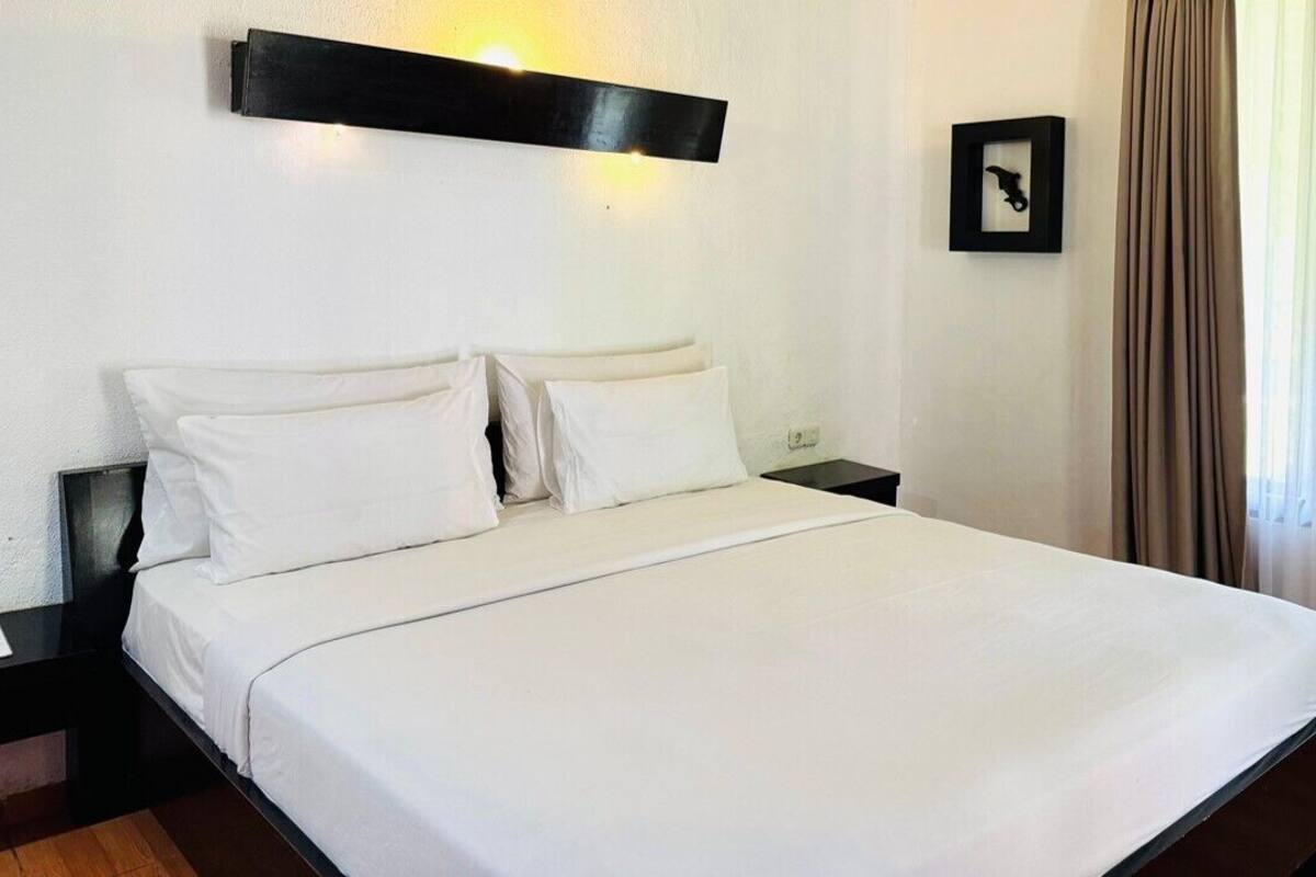 A neatly made bed with white linens in a hotel room.